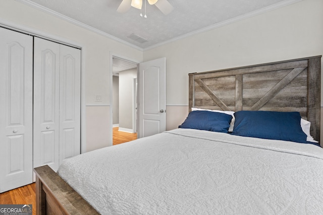 bedroom with crown molding, hardwood / wood-style flooring, a closet, and ceiling fan