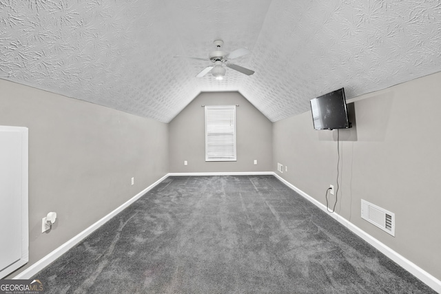 bonus room with ceiling fan, dark carpet, vaulted ceiling, and a textured ceiling