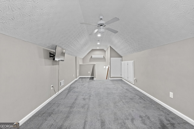 additional living space featuring vaulted ceiling, an AC wall unit, carpet floors, ceiling fan, and a textured ceiling