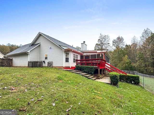 rear view of property featuring a sunroom, a deck, and a lawn