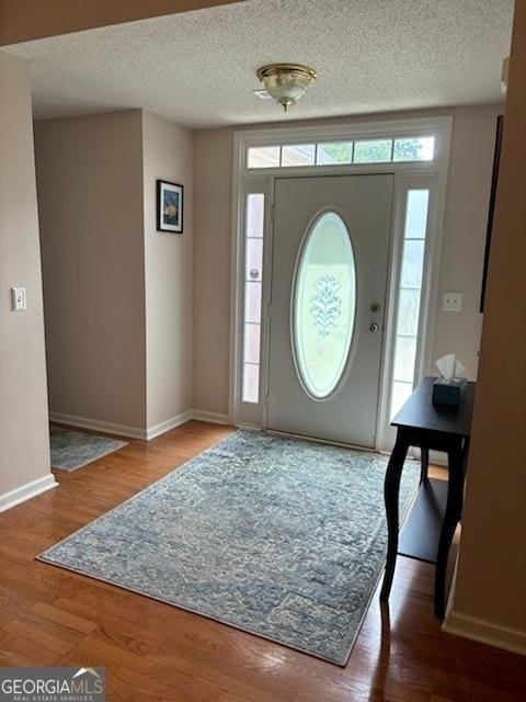 foyer entrance featuring hardwood / wood-style flooring and a textured ceiling