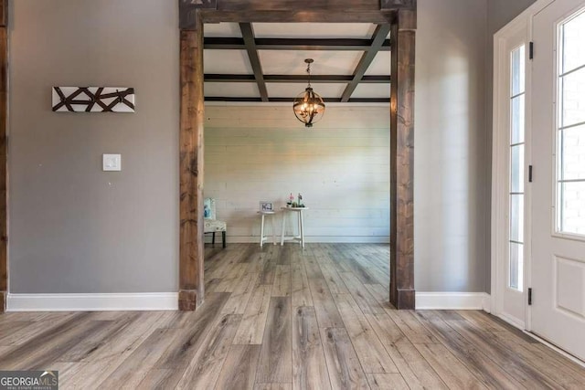 foyer with beamed ceiling, coffered ceiling, hardwood / wood-style floors, and a notable chandelier