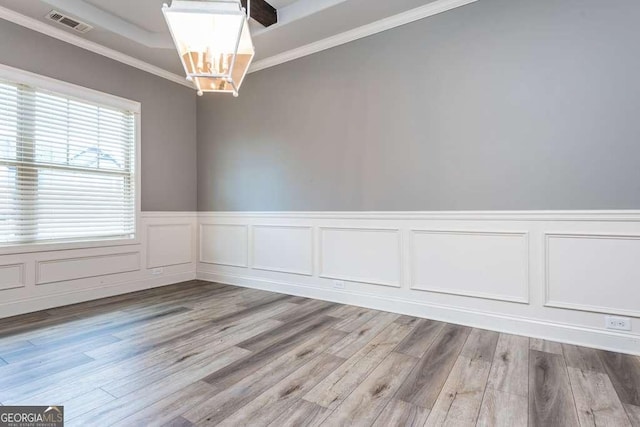 empty room featuring crown molding, light hardwood / wood-style floors, and a chandelier