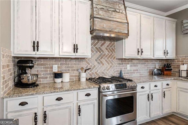 kitchen with tasteful backsplash, white cabinetry, custom exhaust hood, ornamental molding, and stainless steel gas range oven