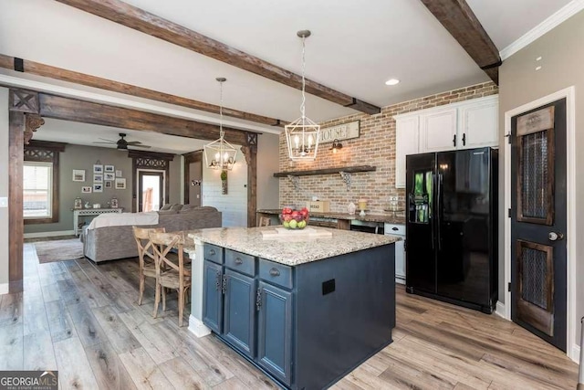 kitchen with blue cabinets, black fridge with ice dispenser, hanging light fixtures, beam ceiling, and white cabinets