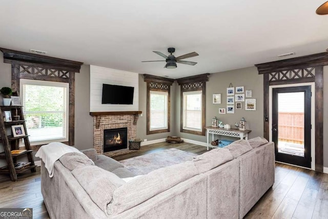 living room featuring a brick fireplace, hardwood / wood-style floors, and ceiling fan