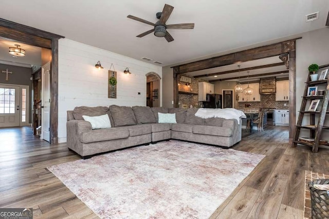 living room featuring beam ceiling, ceiling fan, and dark hardwood / wood-style flooring