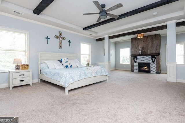 carpeted bedroom with beamed ceiling, ceiling fan, ornamental molding, and a fireplace