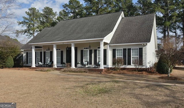 cape cod house featuring covered porch and a front yard