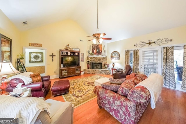 living room with hardwood / wood-style flooring, ceiling fan, high vaulted ceiling, and a fireplace