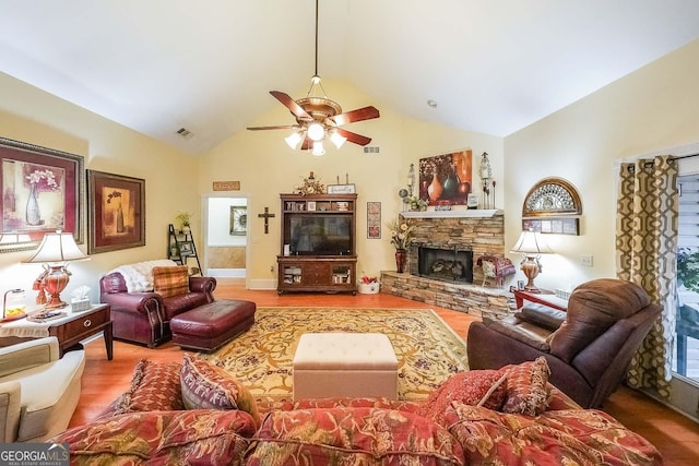 living room featuring ceiling fan, a stone fireplace, high vaulted ceiling, and hardwood / wood-style floors