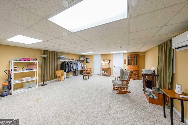 living area featuring carpet flooring, a drop ceiling, and an AC wall unit