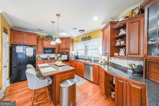 kitchen featuring a kitchen island, a breakfast bar, decorative light fixtures, ornamental molding, and black appliances