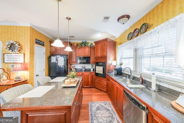 kitchen featuring sink, a kitchen island, ornamental molding, black appliances, and a kitchen bar