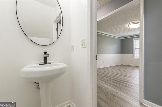 bathroom featuring crown molding, hardwood / wood-style flooring, and a textured ceiling