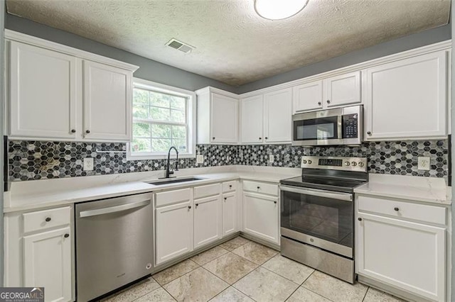 kitchen with appliances with stainless steel finishes, sink, decorative backsplash, and white cabinets