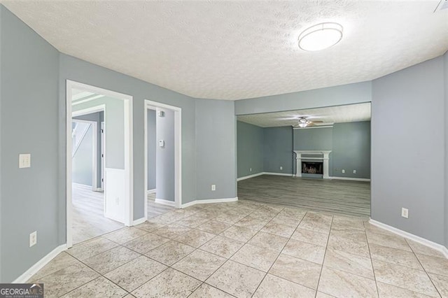 unfurnished living room featuring light tile patterned flooring, ceiling fan, and a textured ceiling