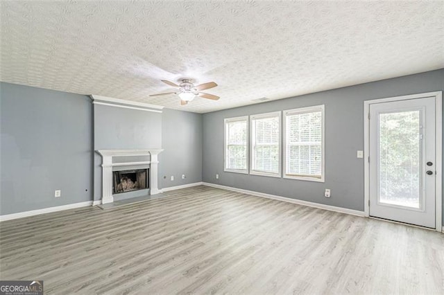 unfurnished living room featuring ceiling fan, light hardwood / wood-style flooring, and a textured ceiling