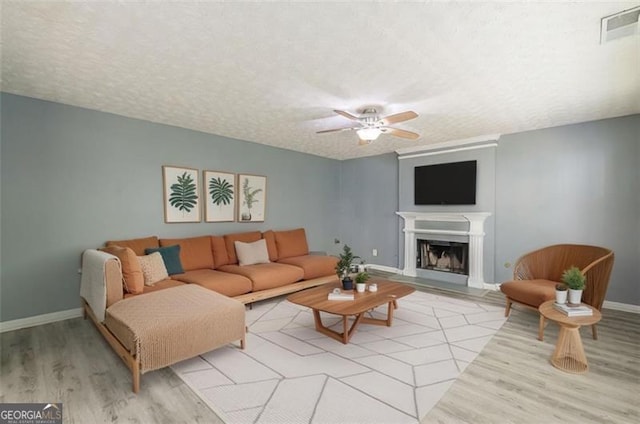 living room featuring ceiling fan, a textured ceiling, and light wood-type flooring