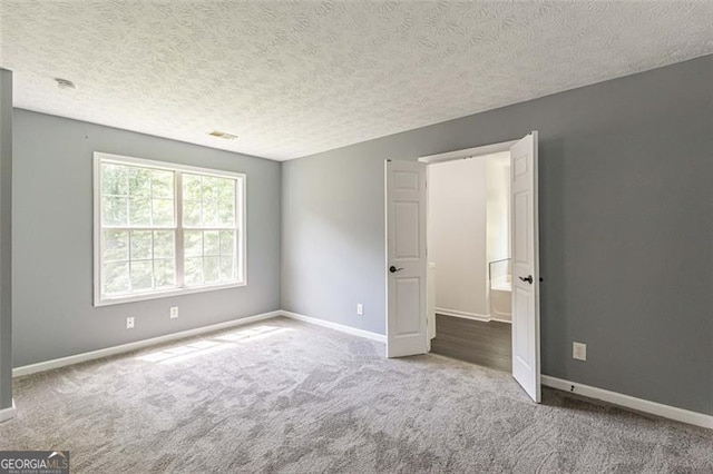 carpeted spare room with a textured ceiling