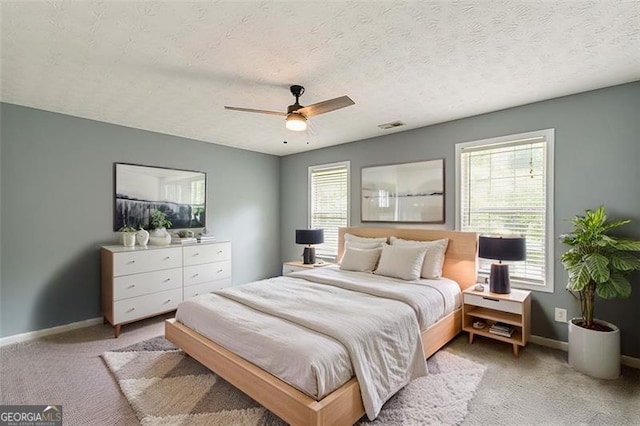 bedroom featuring light carpet, a textured ceiling, and ceiling fan