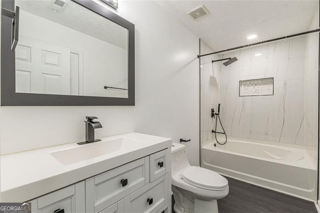 full bathroom with tiled shower / bath combo, vanity, hardwood / wood-style flooring, toilet, and a textured ceiling