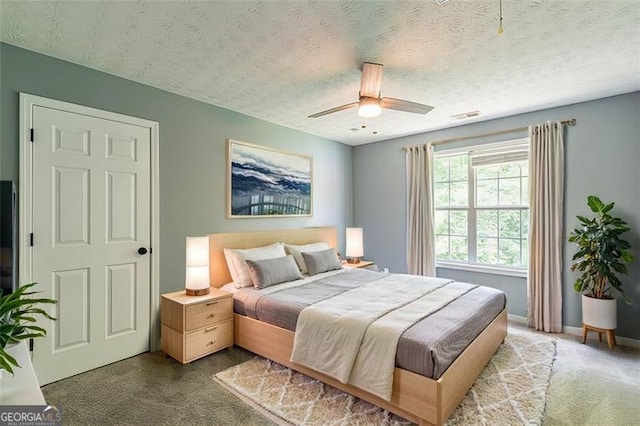 bedroom featuring ceiling fan, carpet floors, and a textured ceiling