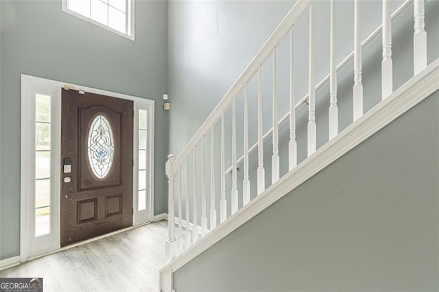 foyer featuring a wealth of natural light, light hardwood / wood-style floors, and a high ceiling