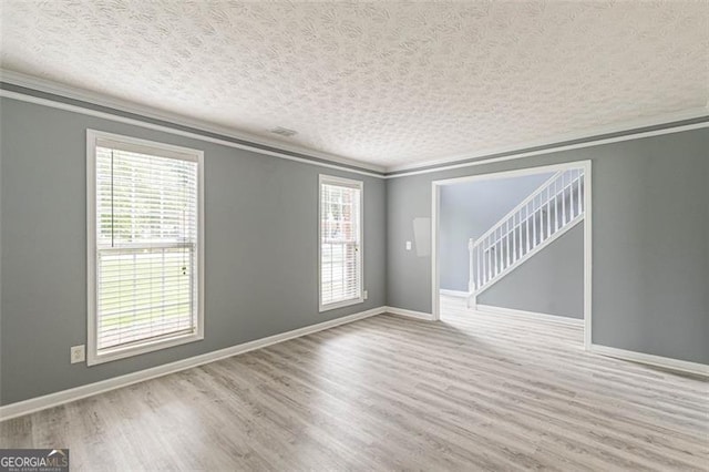 empty room with ornamental molding, hardwood / wood-style floors, and a textured ceiling