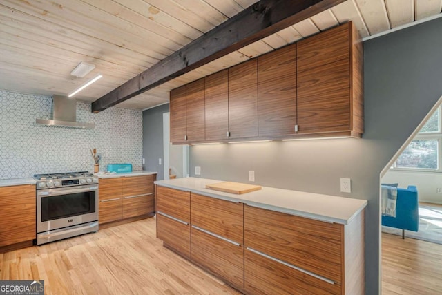 kitchen with light hardwood / wood-style flooring, beam ceiling, tasteful backsplash, stainless steel gas range oven, and wall chimney exhaust hood