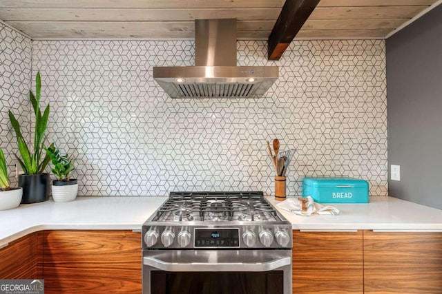 kitchen featuring stainless steel gas range oven, exhaust hood, beam ceiling, and decorative backsplash