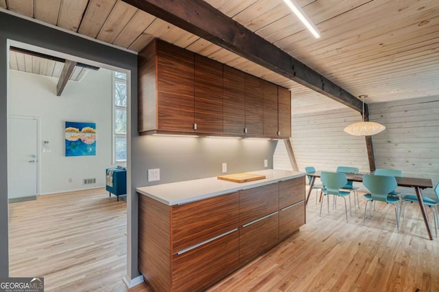 kitchen with pendant lighting, wooden ceiling, beam ceiling, and light hardwood / wood-style flooring