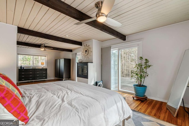 bedroom featuring multiple windows, hardwood / wood-style flooring, access to outside, and beamed ceiling