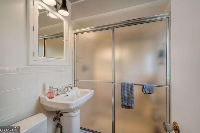 bathroom with tile walls, an enclosed shower, and toilet