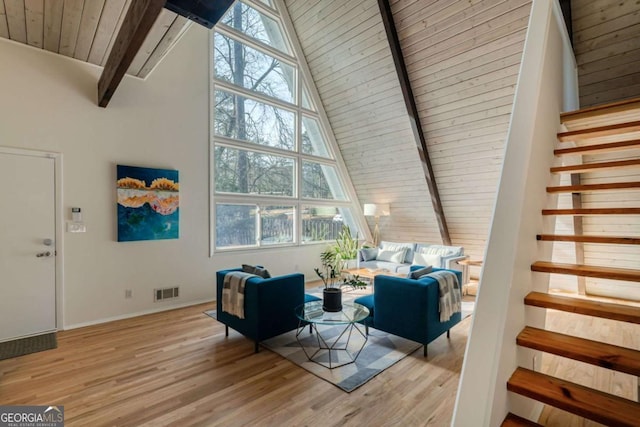 living room featuring beamed ceiling, light wood-type flooring, a wealth of natural light, and wood ceiling