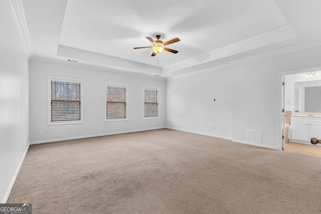 spare room featuring ceiling fan, light colored carpet, crown molding, and a raised ceiling