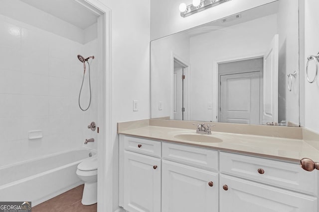 full bathroom with tile patterned flooring, vanity, tiled shower / bath, and toilet