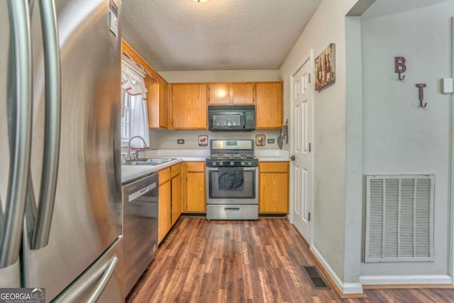 kitchen featuring appliances with stainless steel finishes, dark hardwood / wood-style flooring, sink, and a textured ceiling