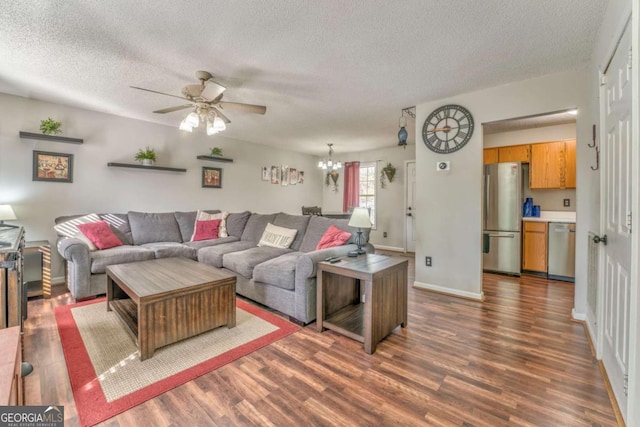 living room featuring ceiling fan with notable chandelier, dark wood-type flooring, and a textured ceiling