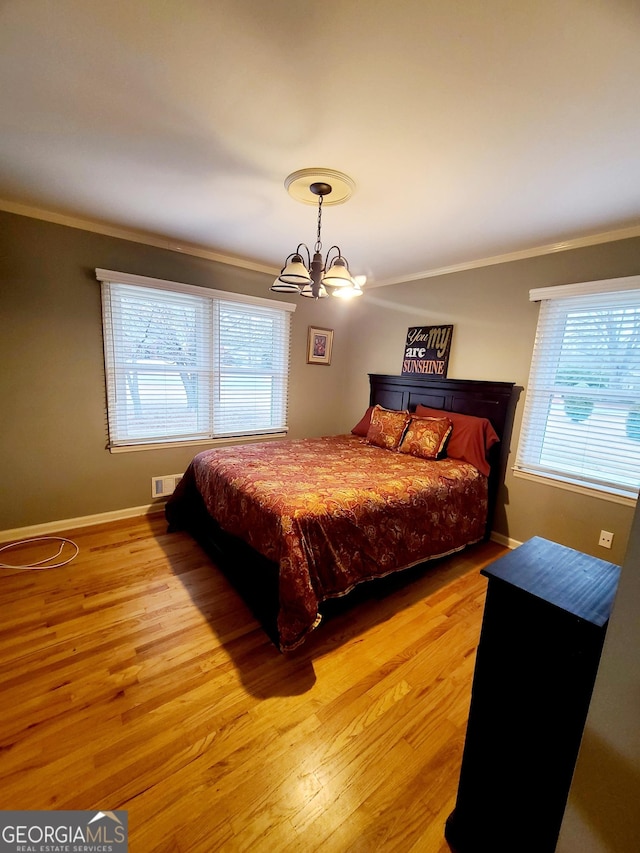 bedroom with multiple windows, ornamental molding, and light hardwood / wood-style flooring