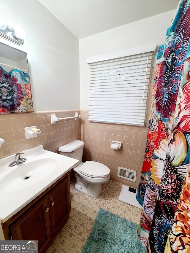 bathroom featuring vanity, tile patterned flooring, toilet, and tile walls