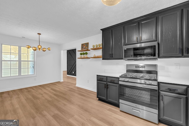 kitchen featuring appliances with stainless steel finishes, pendant lighting, a textured ceiling, and light hardwood / wood-style flooring