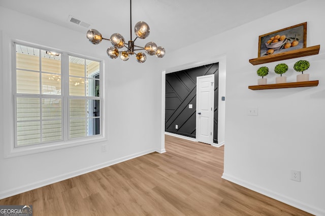 unfurnished dining area with light hardwood / wood-style flooring and a notable chandelier