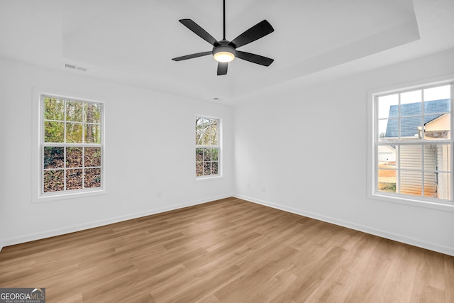 unfurnished room featuring ceiling fan, a raised ceiling, and light hardwood / wood-style floors