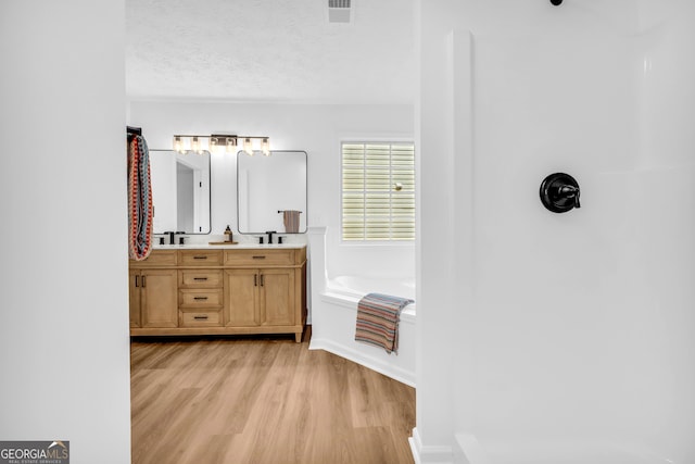 bathroom featuring vanity, a tub to relax in, hardwood / wood-style flooring, and a textured ceiling