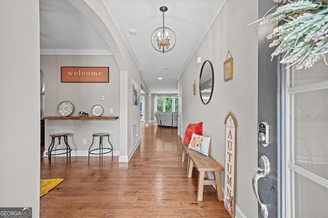 foyer featuring wood-type flooring, a chandelier, and crown molding