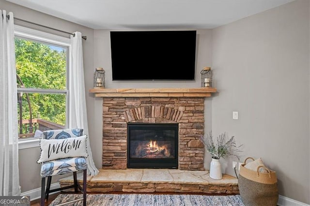 living area featuring a stone fireplace and a healthy amount of sunlight