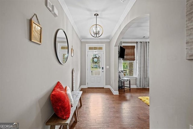 foyer with ornamental molding, an inviting chandelier, and dark hardwood / wood-style flooring