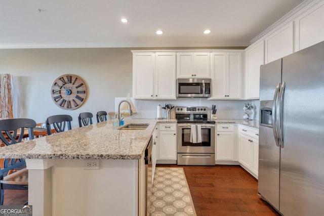 kitchen with sink, appliances with stainless steel finishes, white cabinets, a kitchen bar, and kitchen peninsula