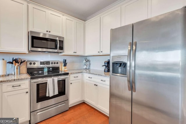 kitchen with white cabinetry, appliances with stainless steel finishes, light stone counters, and light hardwood / wood-style flooring